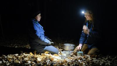 To spejdere i mærket på knæ rund om et stormkøkken